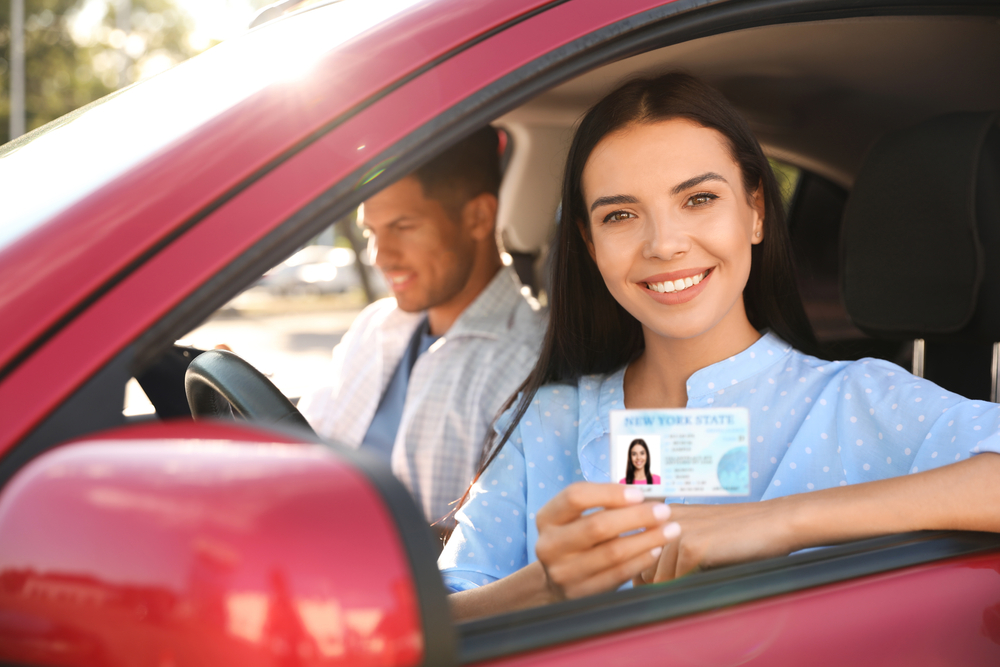 Young,Woman,Holding,License,While,Sitting,In,Car,With,Instructor.