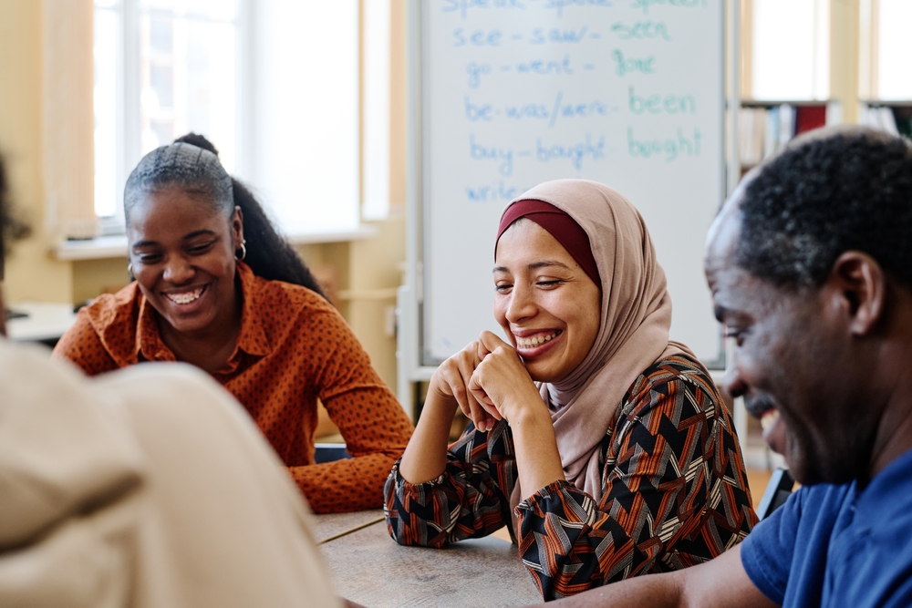Group,Of,Modern,Immigrants,Sitting,At,Table,Having,Fun,Laughing