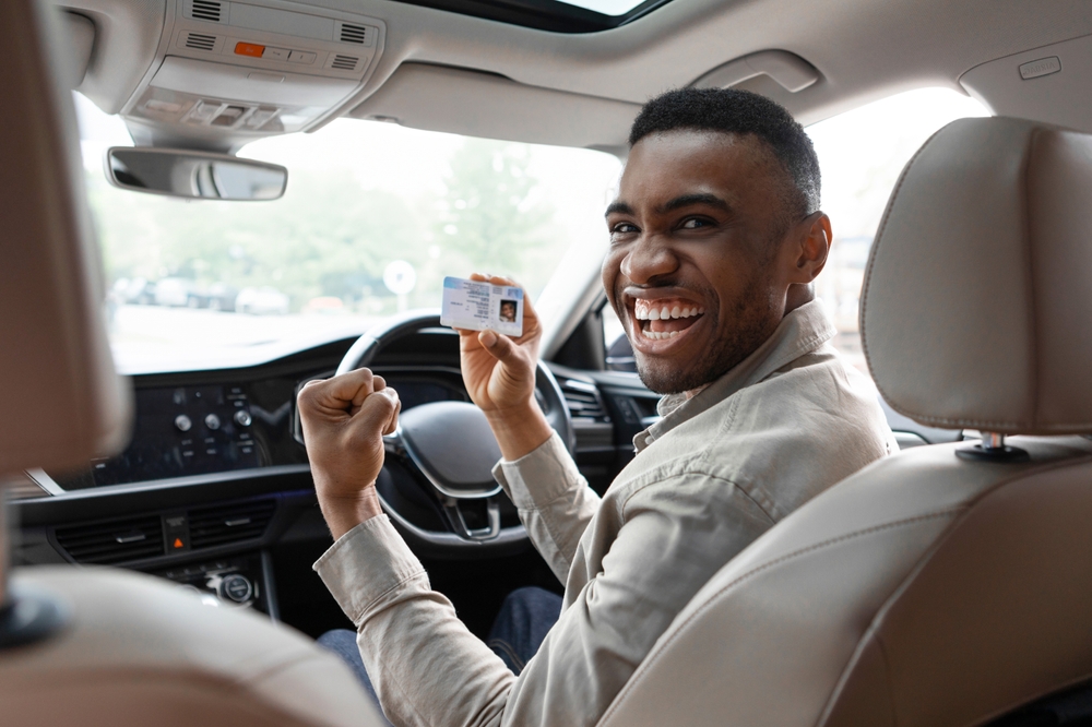 Happy,Young,African,Man,Showing,His,Driver's,License,While,Driving