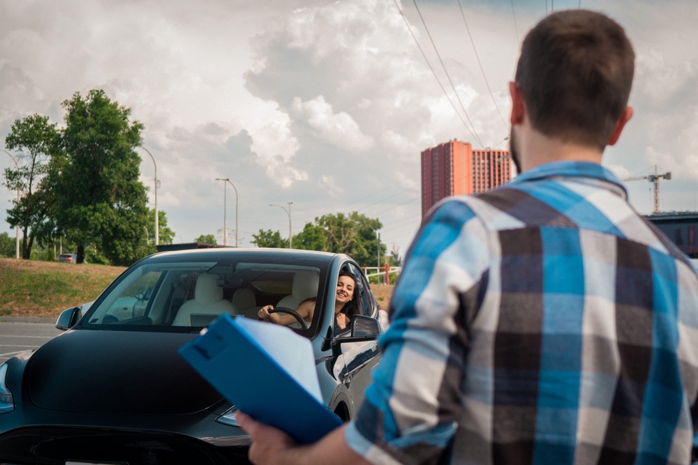 Male,Instructor,Standing,Outdoor,During,Driving,Exam,,Holding,Test,Report.